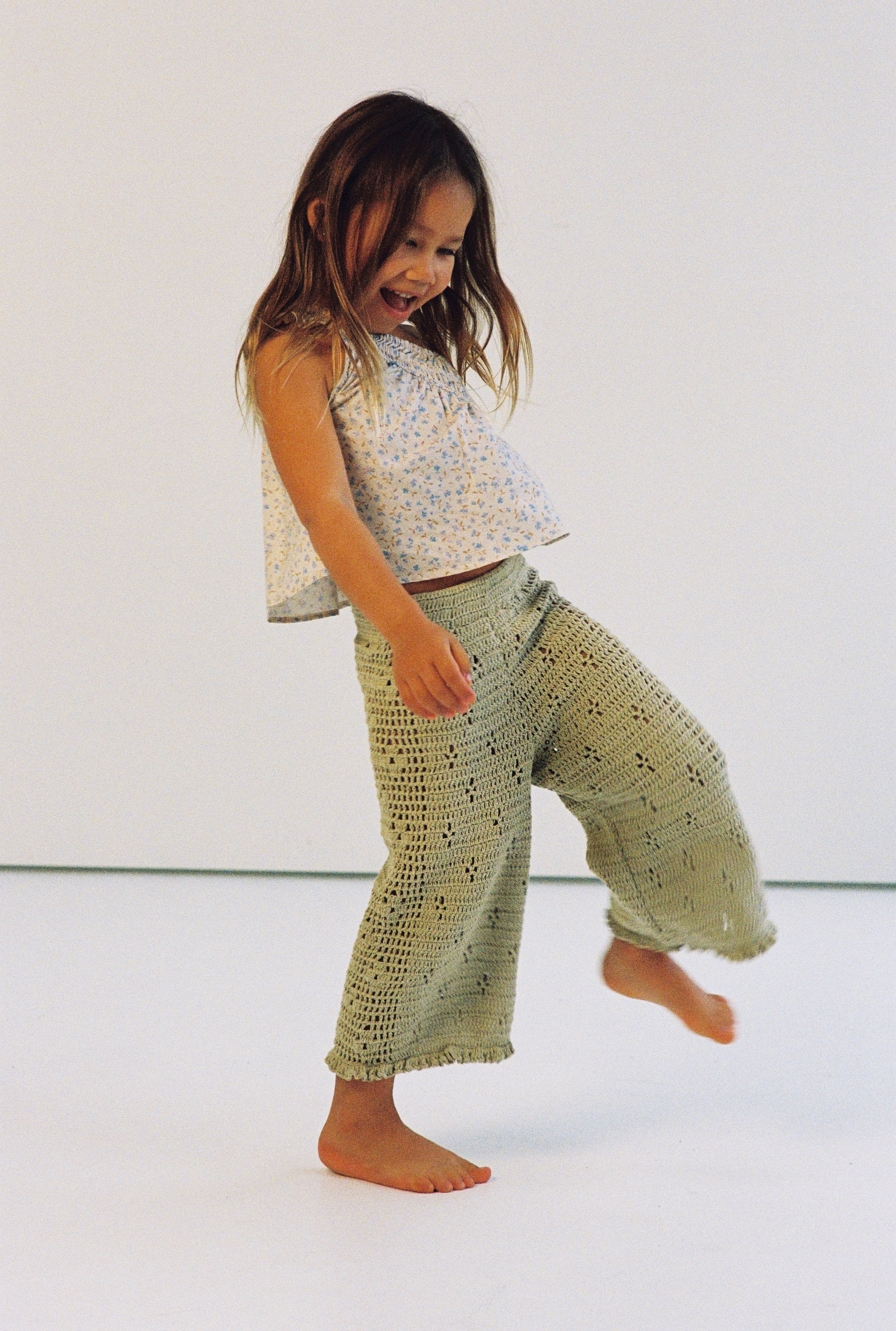 girl wearing one shoulder floral print top with gathers in 100% cotton poplin and 100% cotton handmade crochet pants
