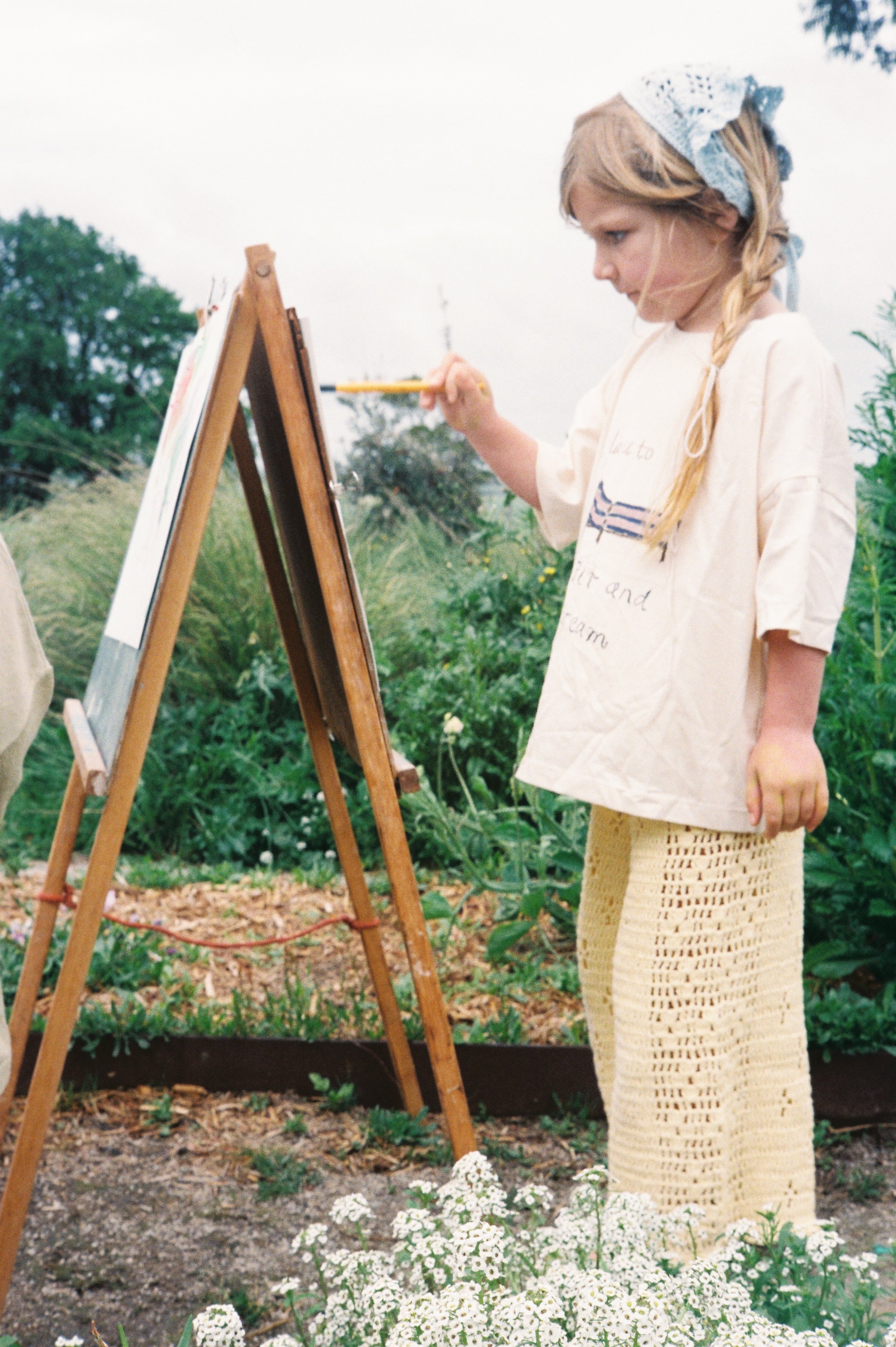 girl painting wearing handmade cotton crochet pants in butter by illoura the label