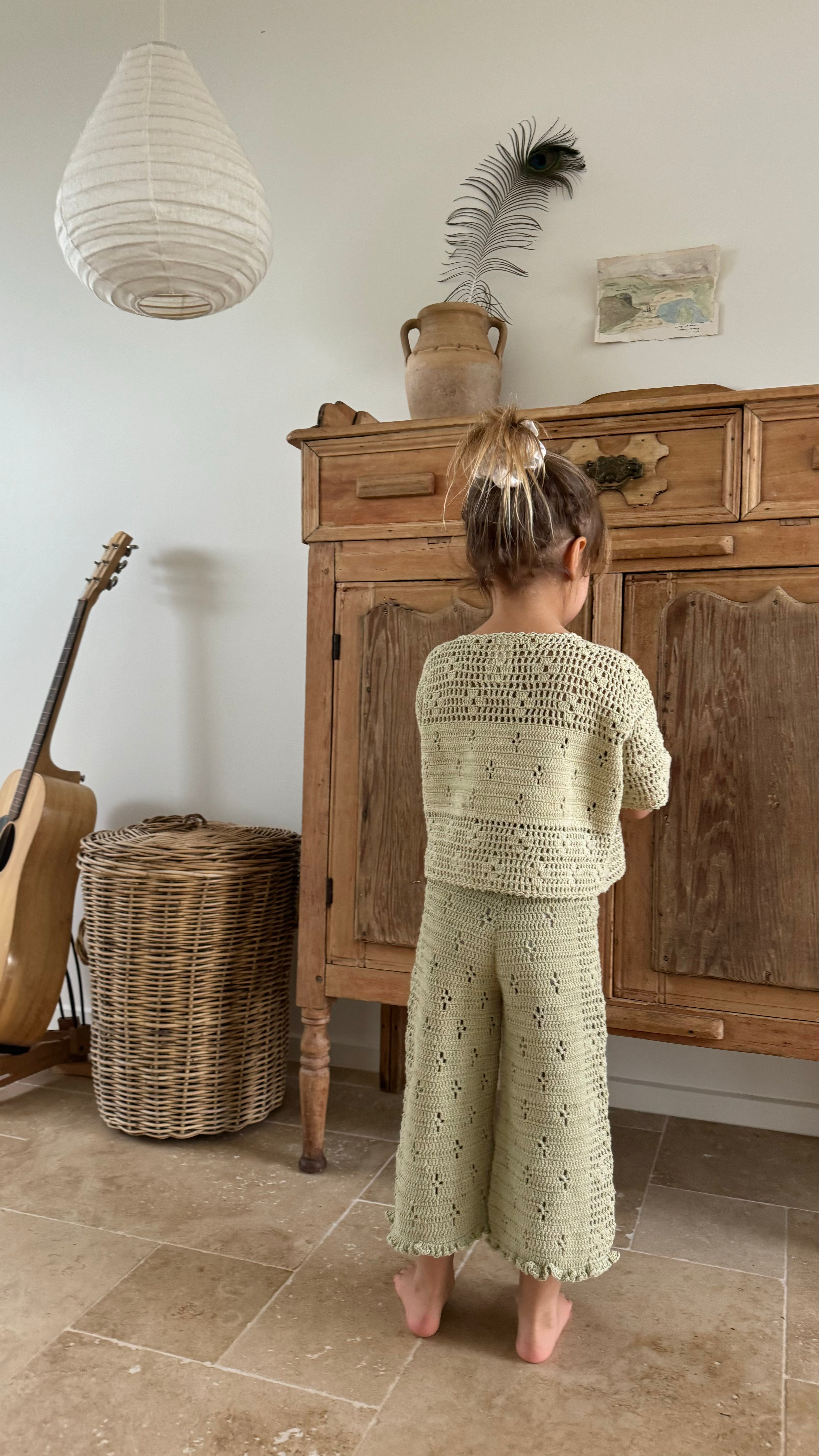 girl wears 100% cotton t-shirt style crochet top in moss green colour featuring floral filet design and 100% cotton crochet pants in moss colour with elasticated waist and floral filet design