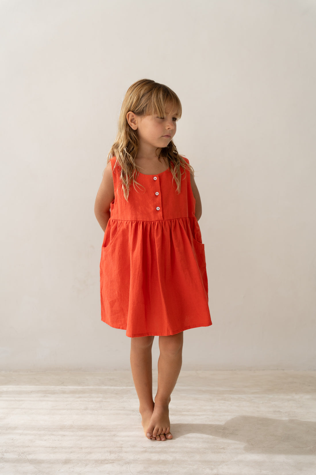 girl wearing cotton pinafore dress in red by Illoura the label