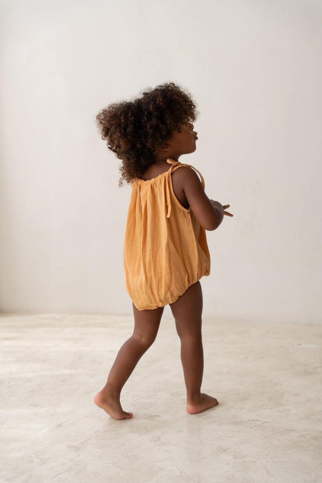 toddler girl wearing orange cotton romper by illoura the label