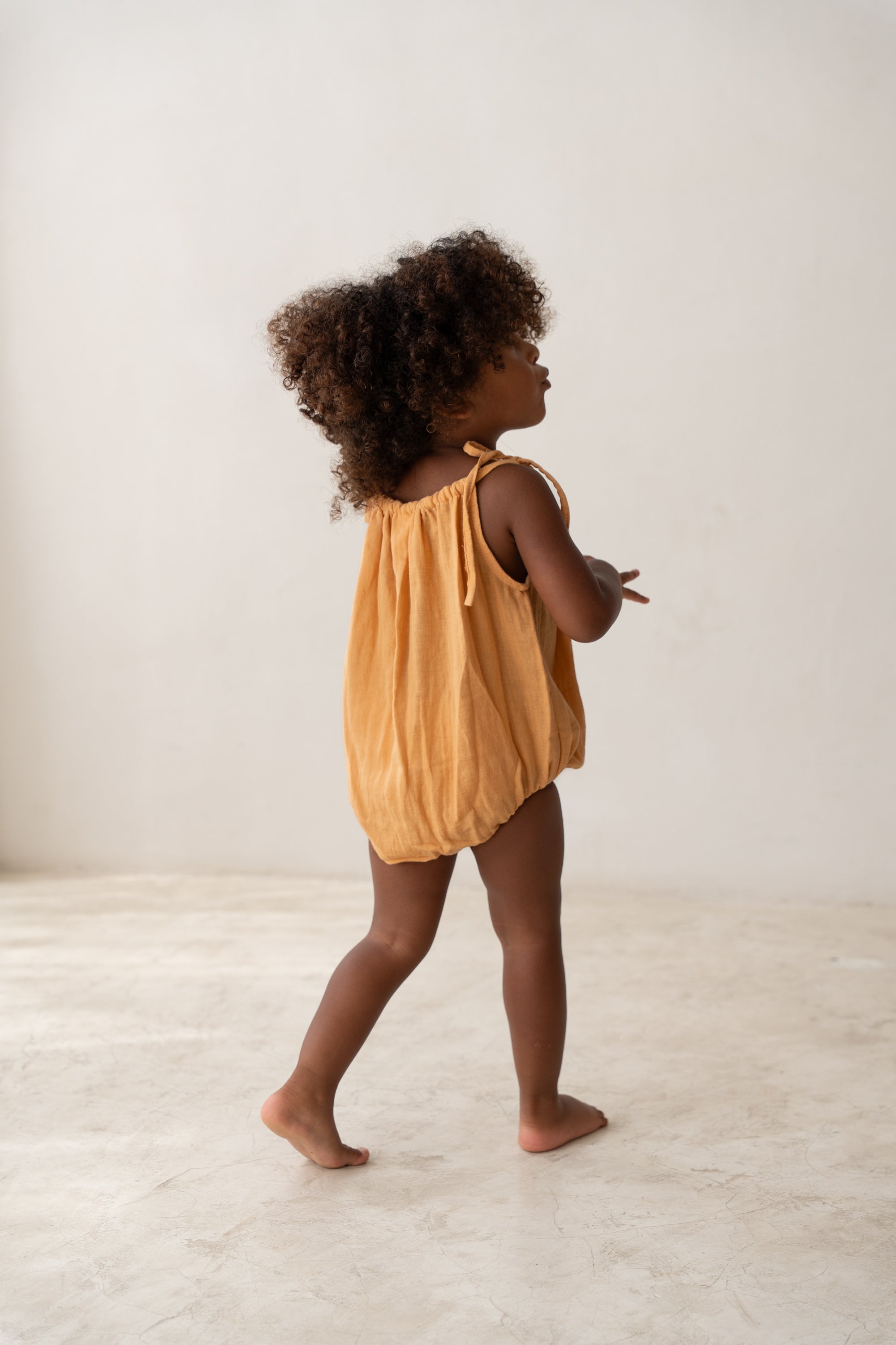 toddler girl wearing orange cotton romper by illoura the label