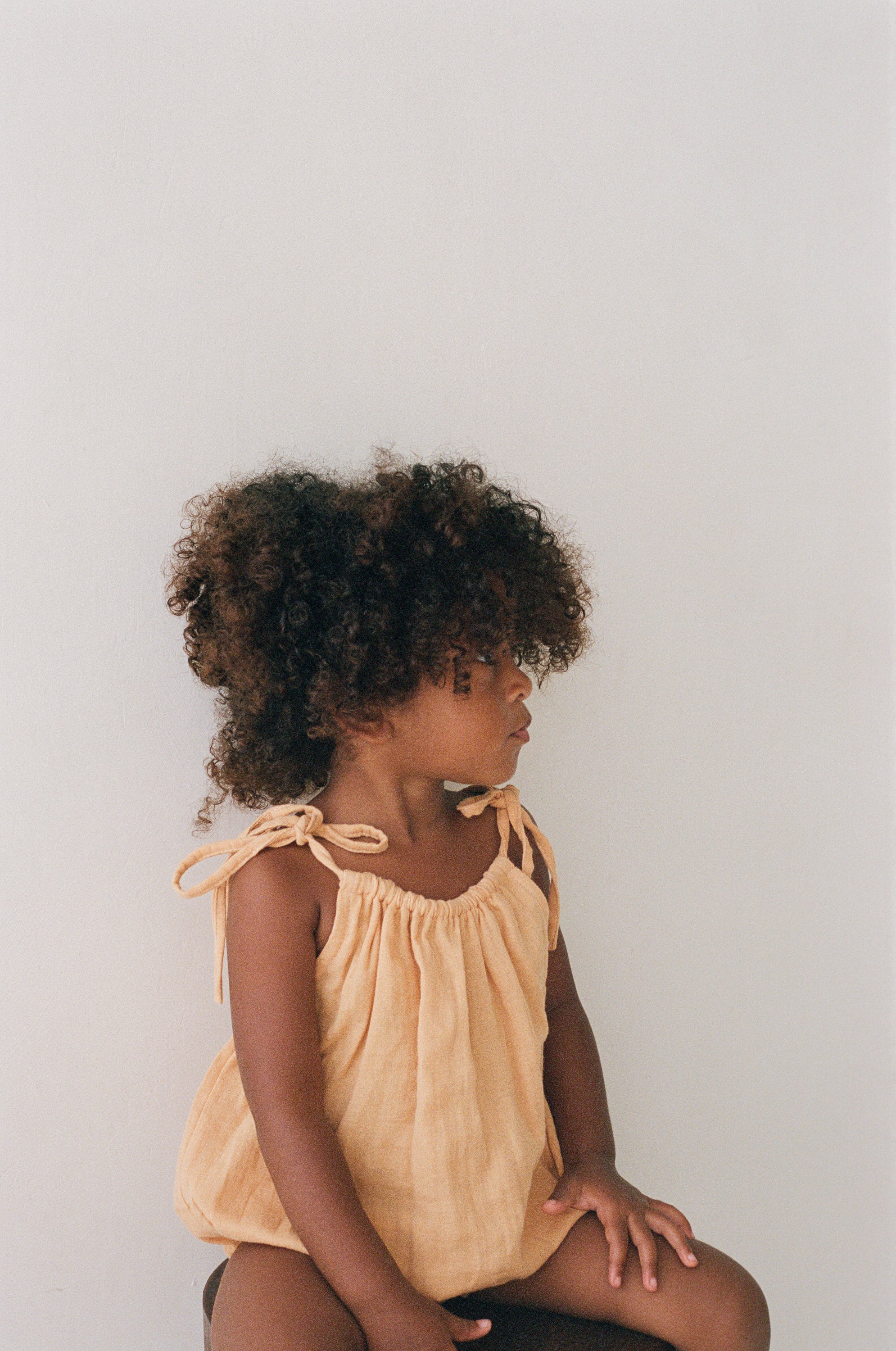 toddler girl wearing orange cotton romper by illoura the label