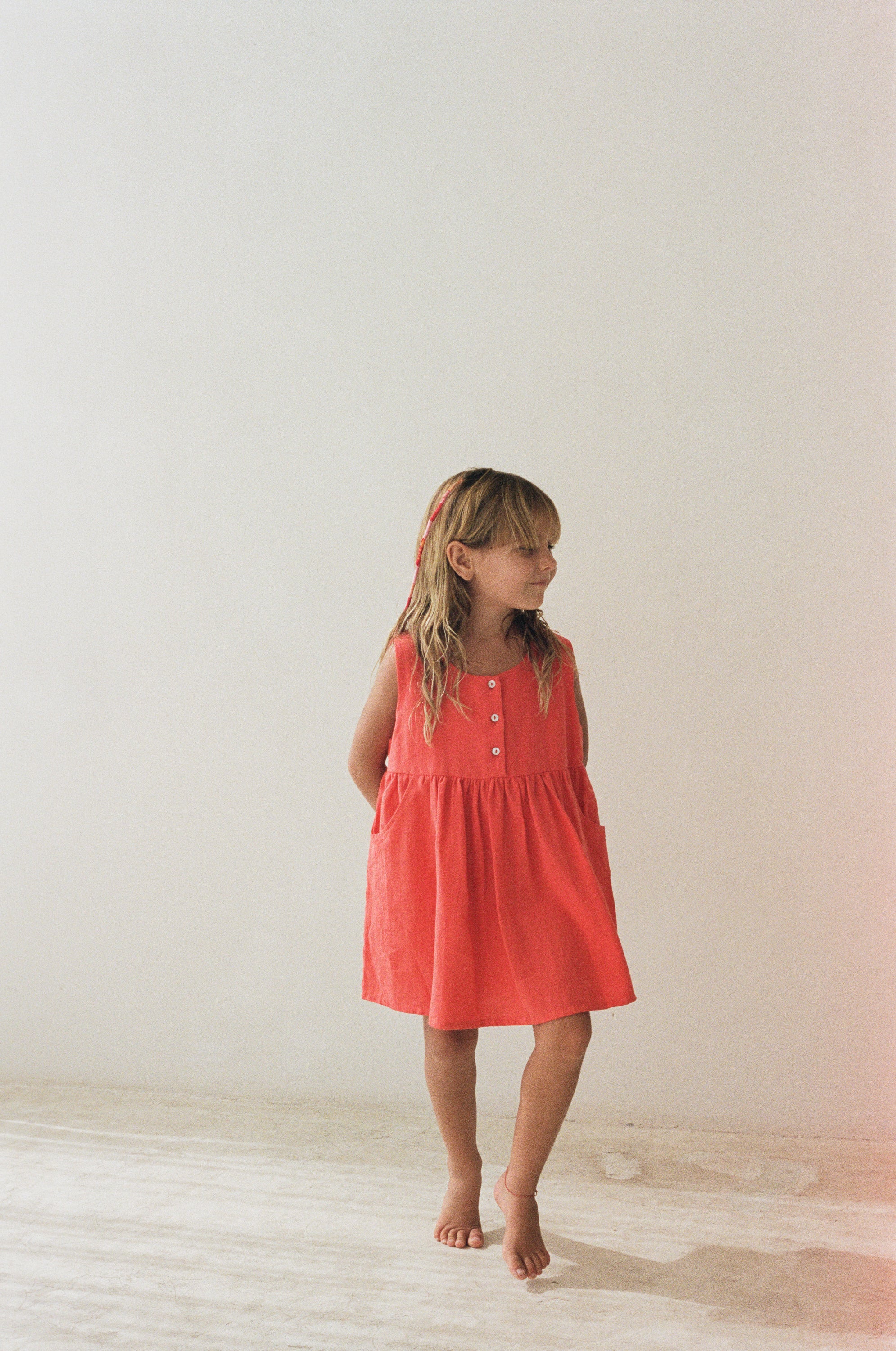 girl wearing cotton pinafore dress in red by Illoura the label