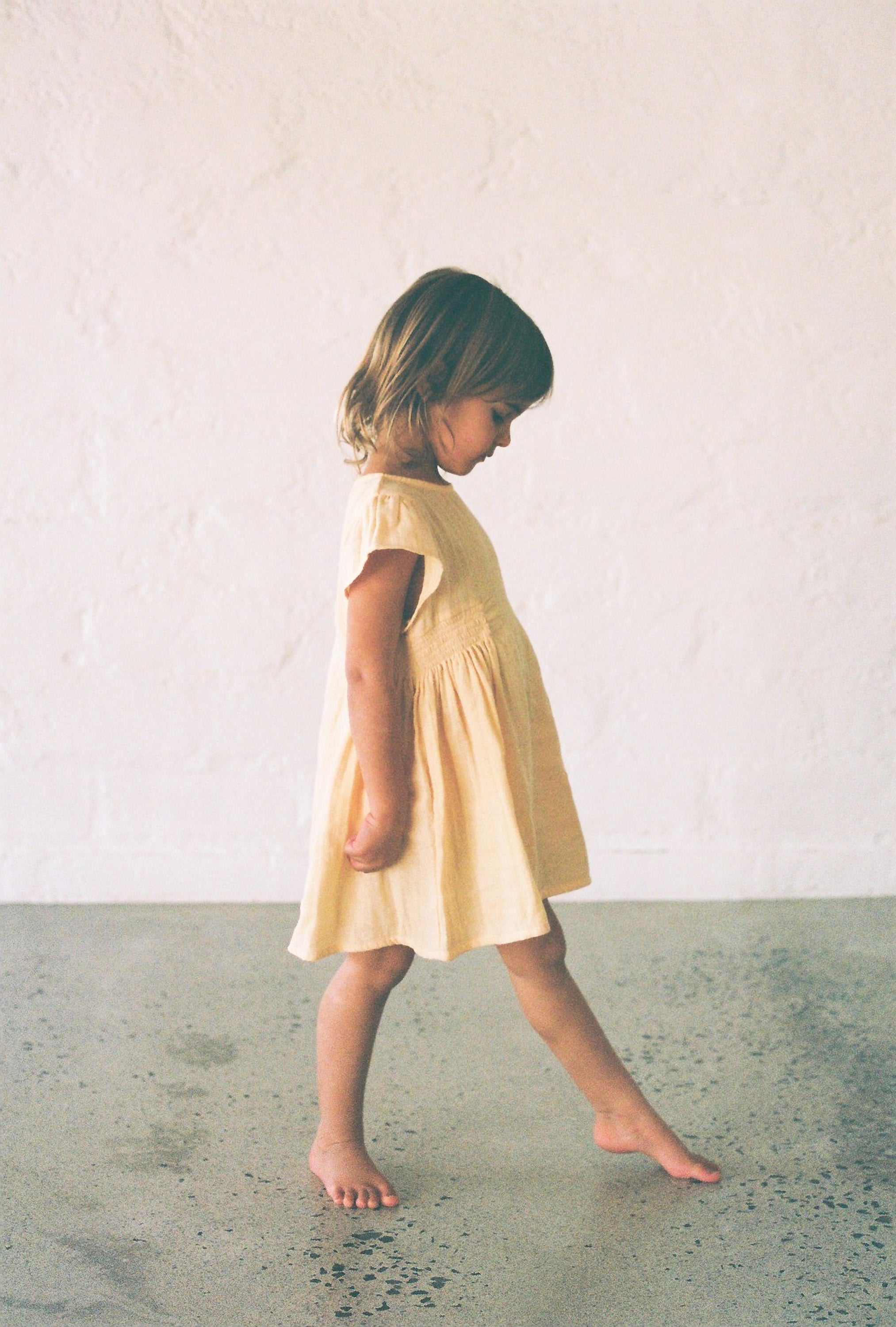 toddler girl wearing 100% cotton dress with shirring and flutter sleeves in butter yellow