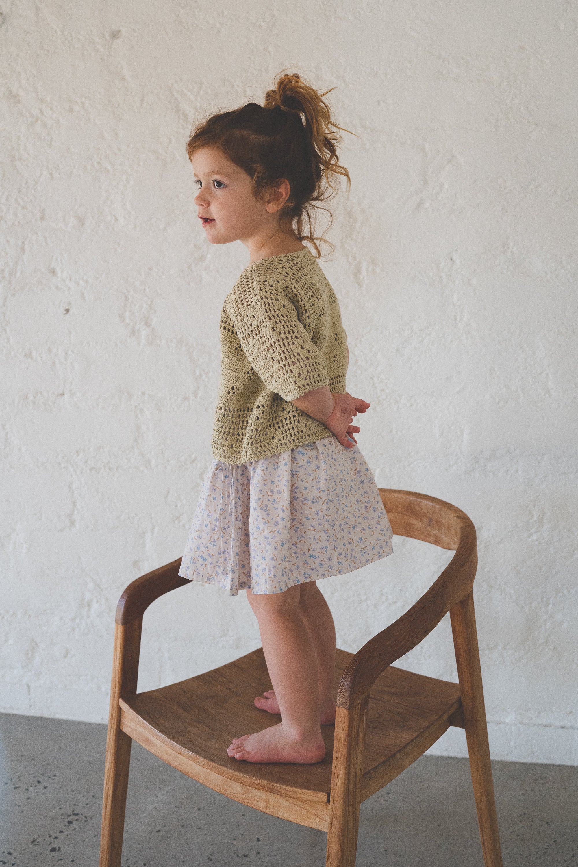 girl wears 100% cotton poplin skirt in blue floral print and 100% cotton hand made crochet top in moss