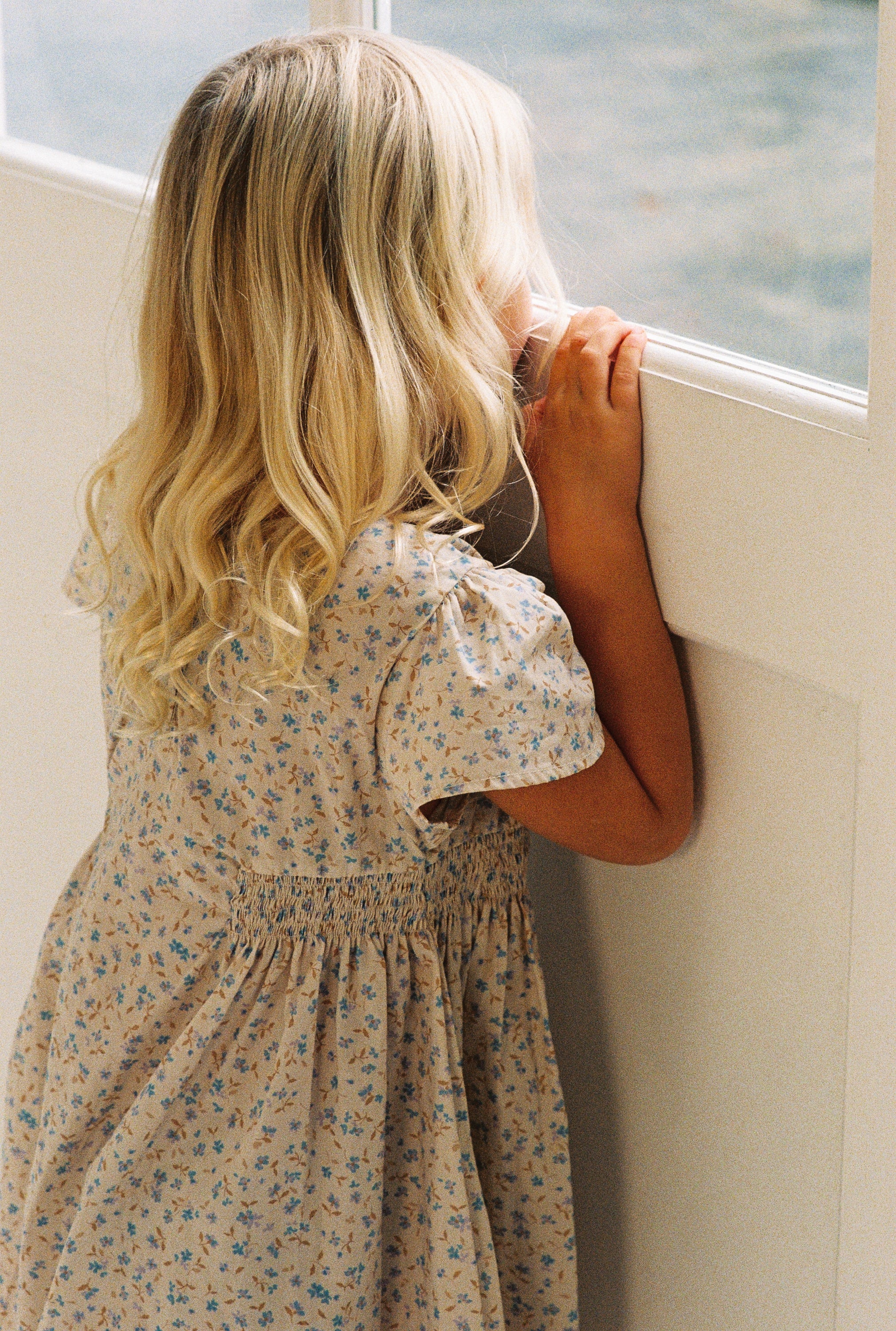 girl wearing floral print mini dress in 100% cotton poplin with shirring and flutter sleeves