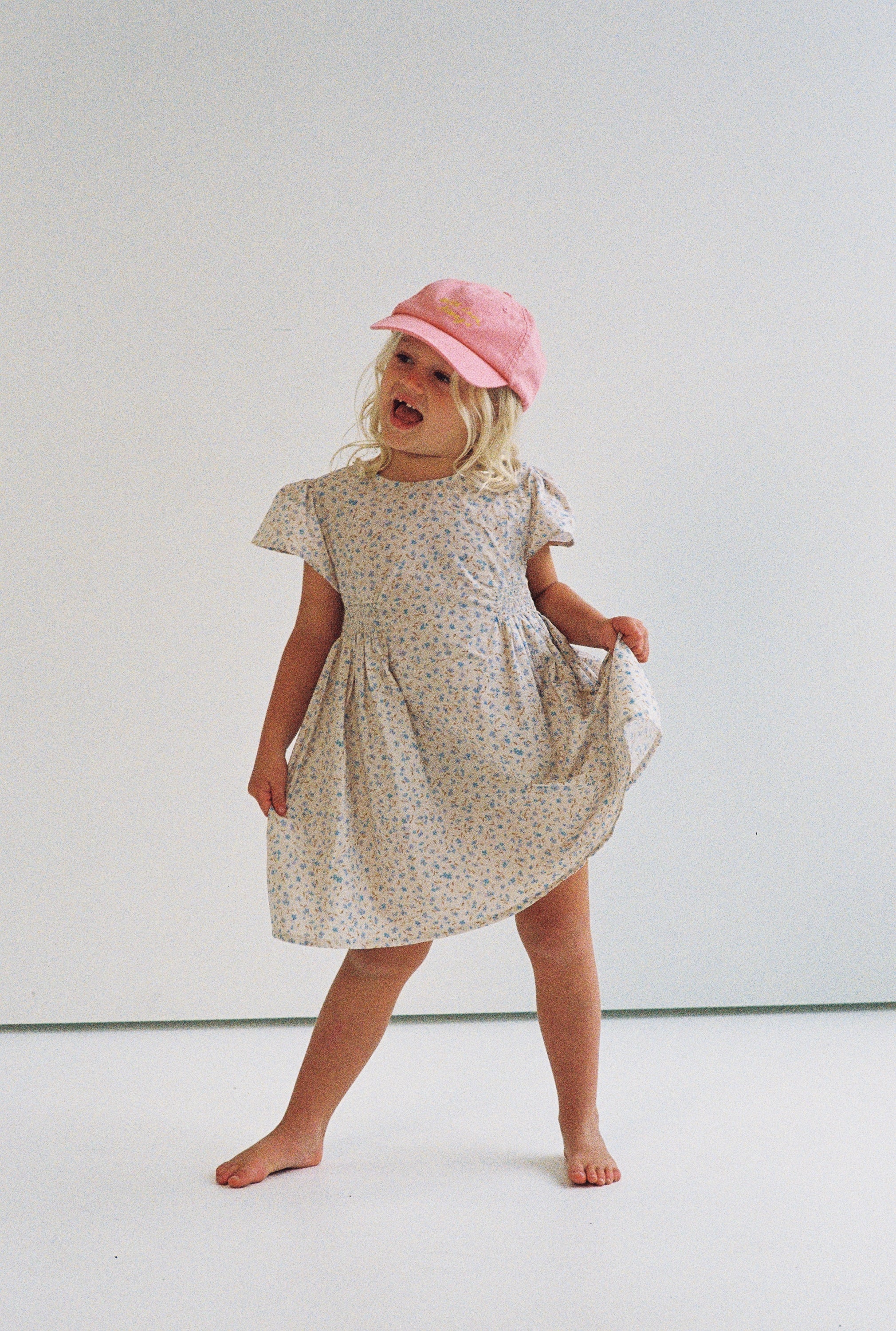 girl wearing floral print mini dress in 100% cotton poplin with shirring and flutter sleeves