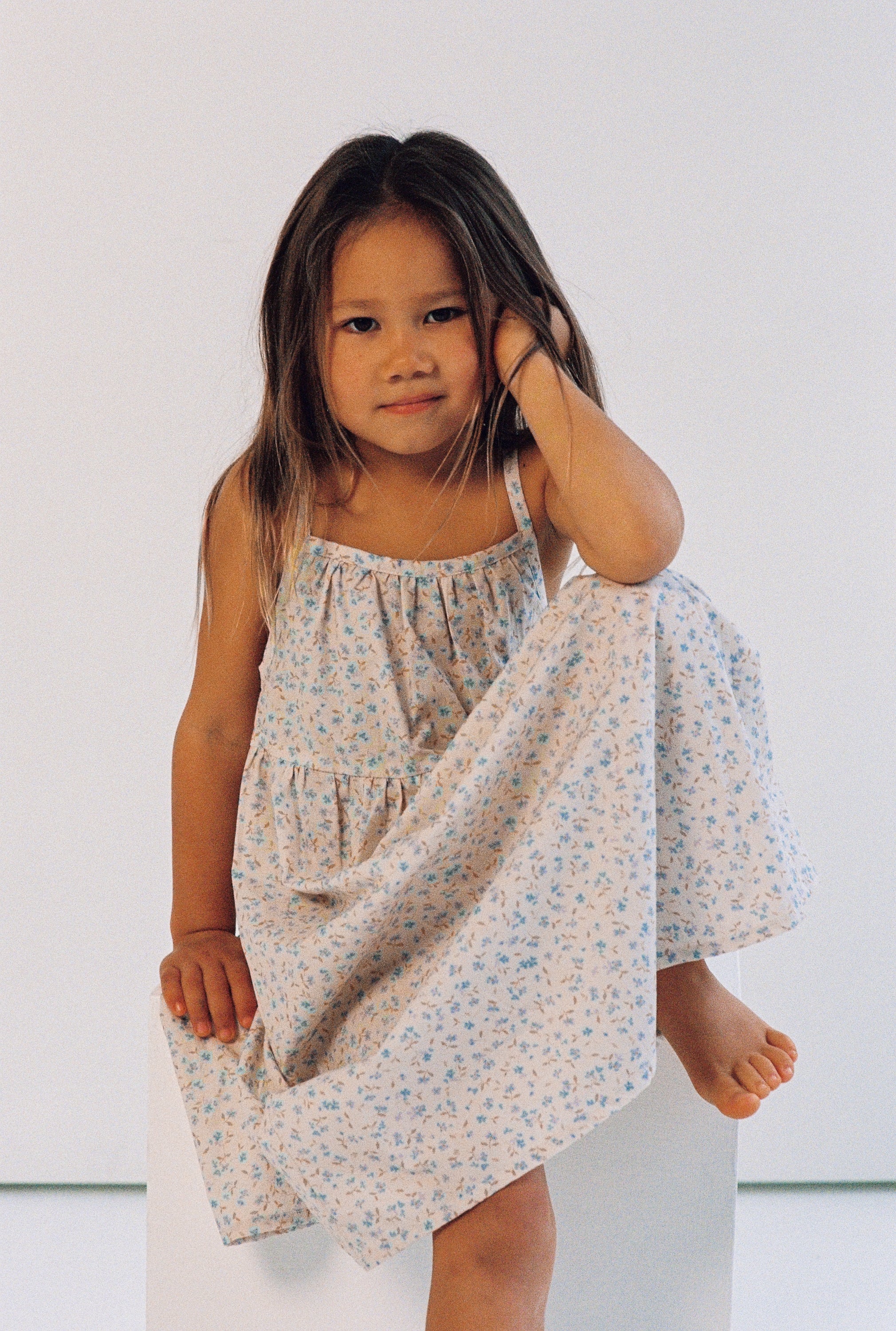 girl wearing 3/4 length floral printed dress made from 100% cotton poplin with thin straps and gathers at the chest and waist