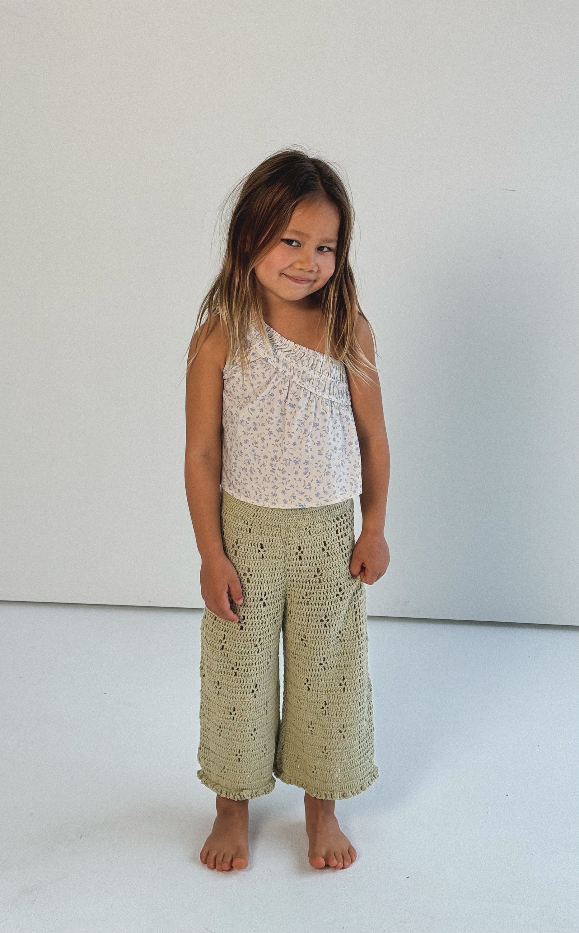 girl wearing one shoulder floral print top with gathers in 100% cotton poplin and 100% cotton handmade crochet pants