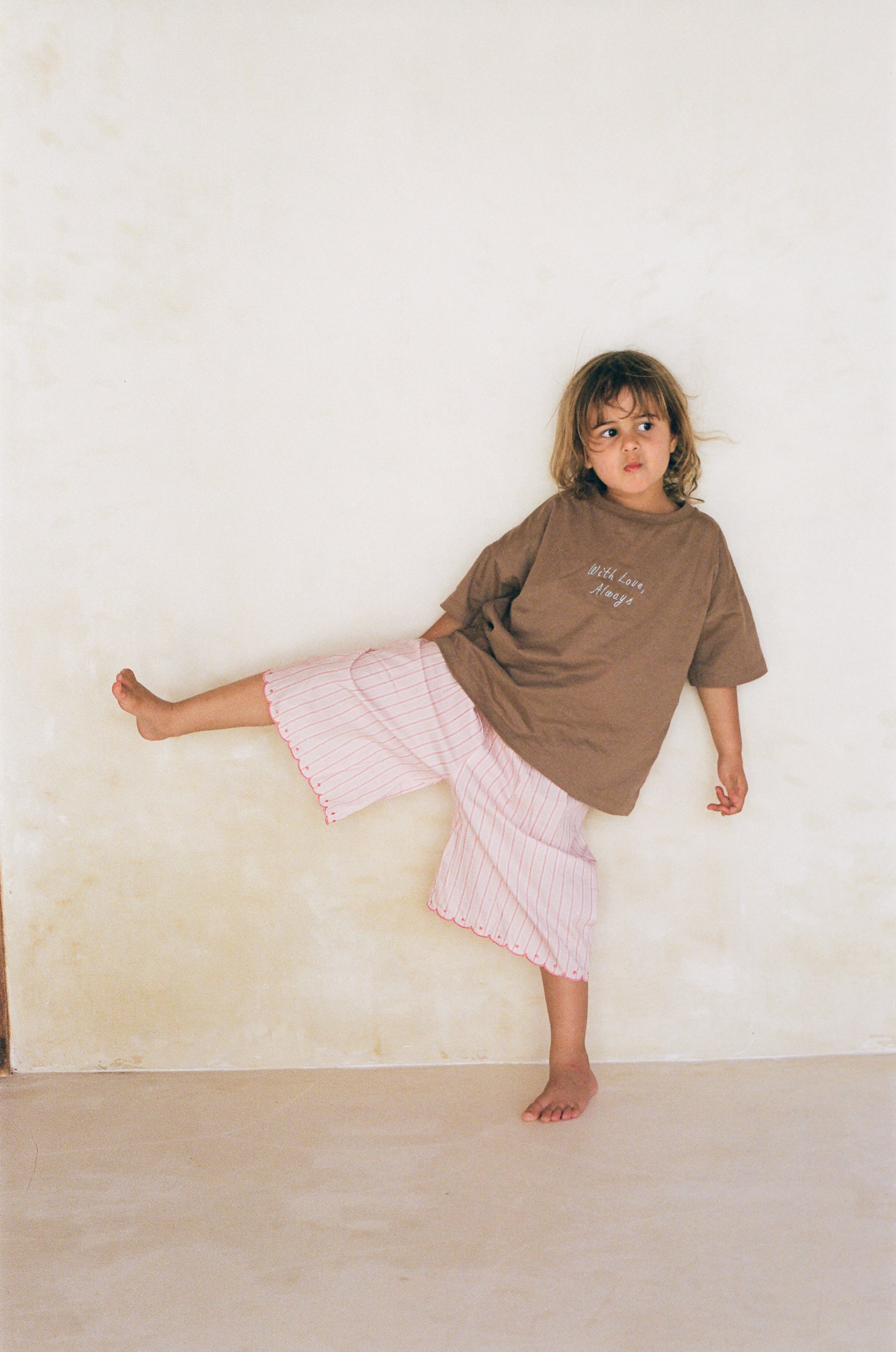 girl wearing cotton pink stripe wide leg pants and brown cotton t-shirt by illoura the label