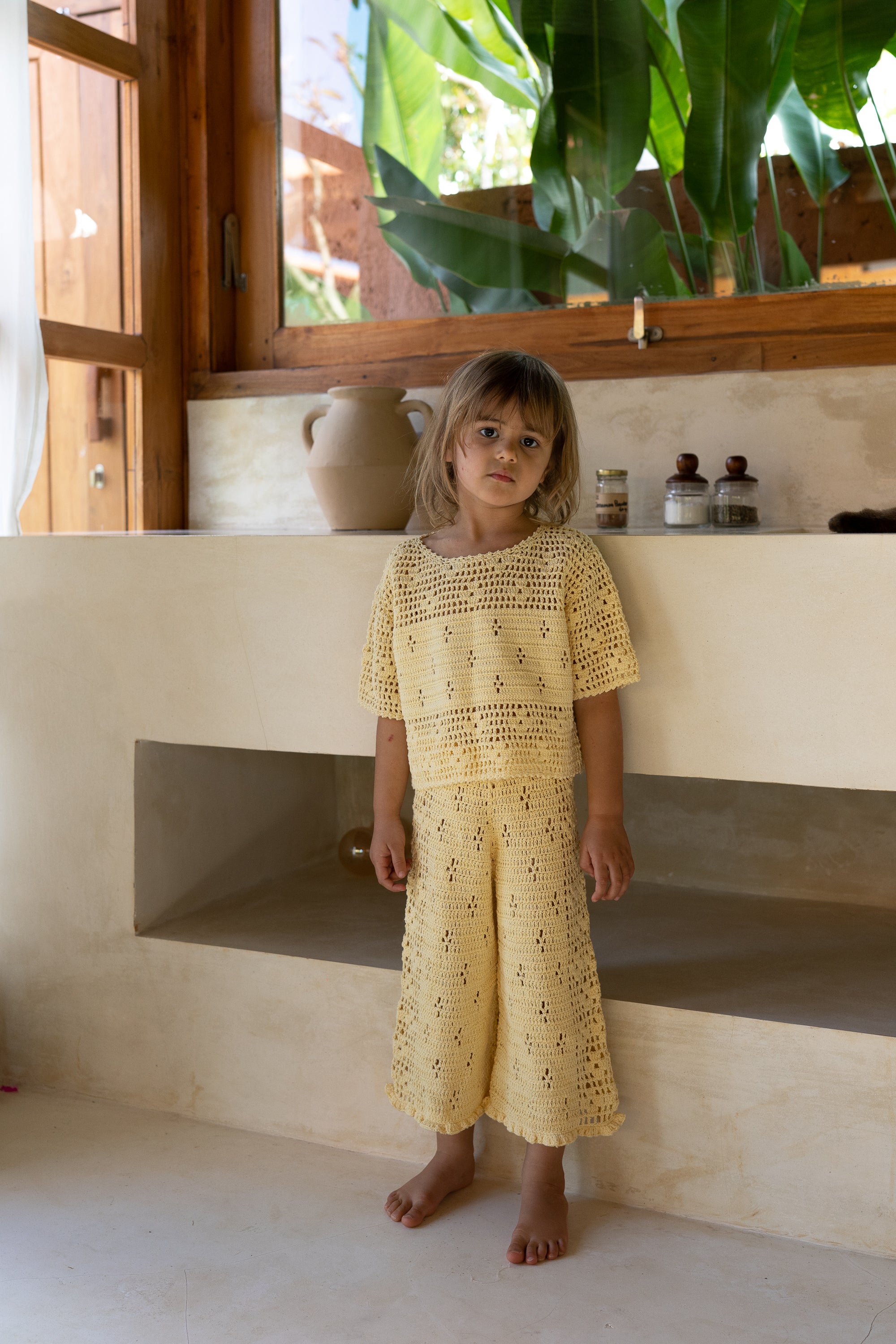 girl wearing handmade cotton crochet top and pants in butter yellow by Illoura the label