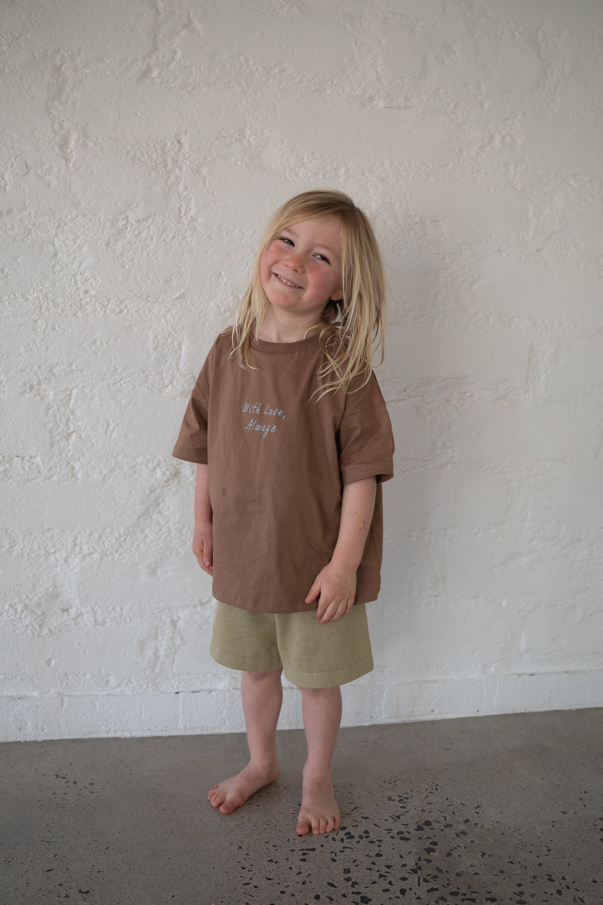 boy wears 100% cotton oversized chocolate tee with blue embroidery