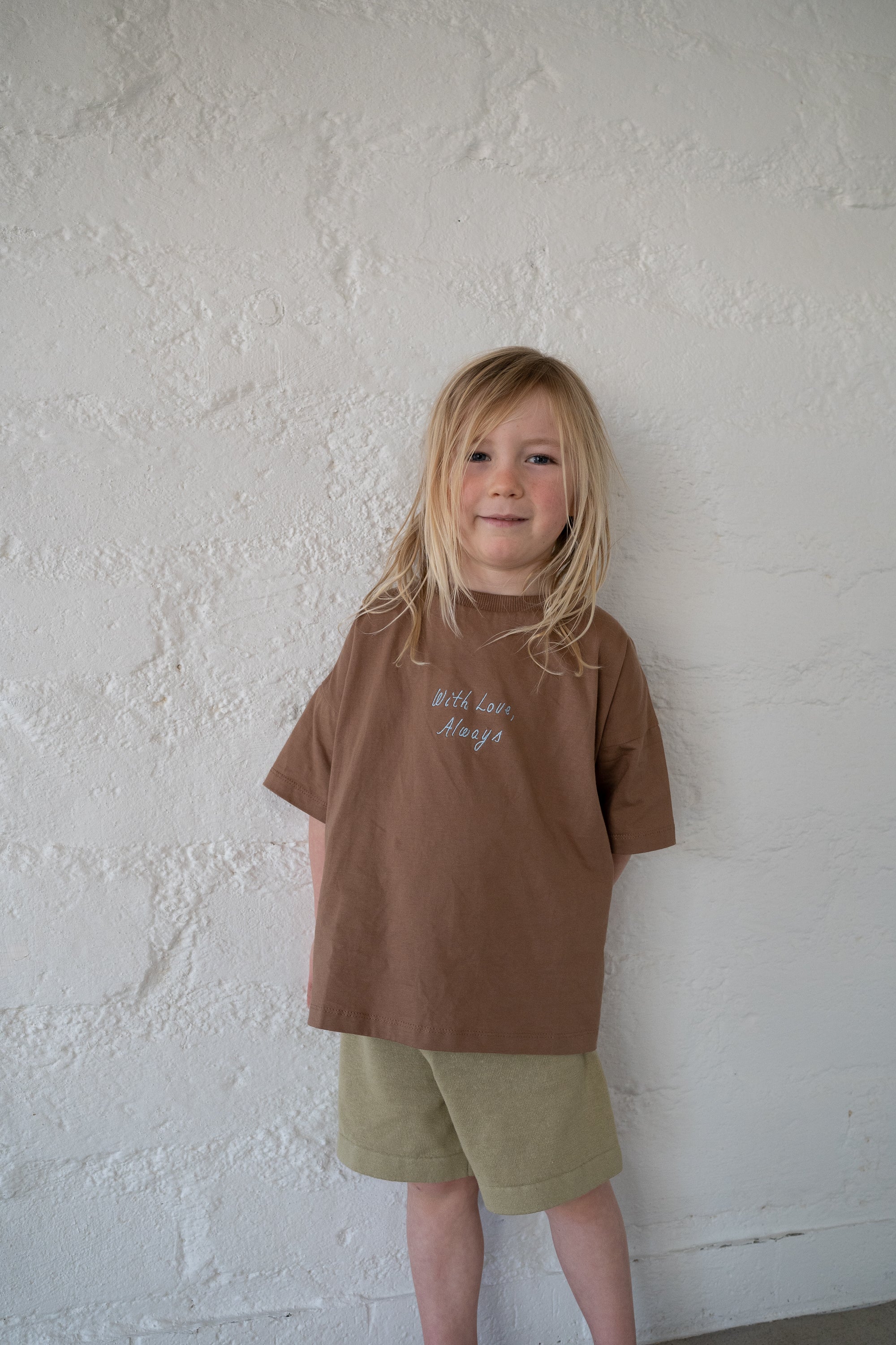 boy wears 100% cotton oversized chocolate tee with blue embroidery