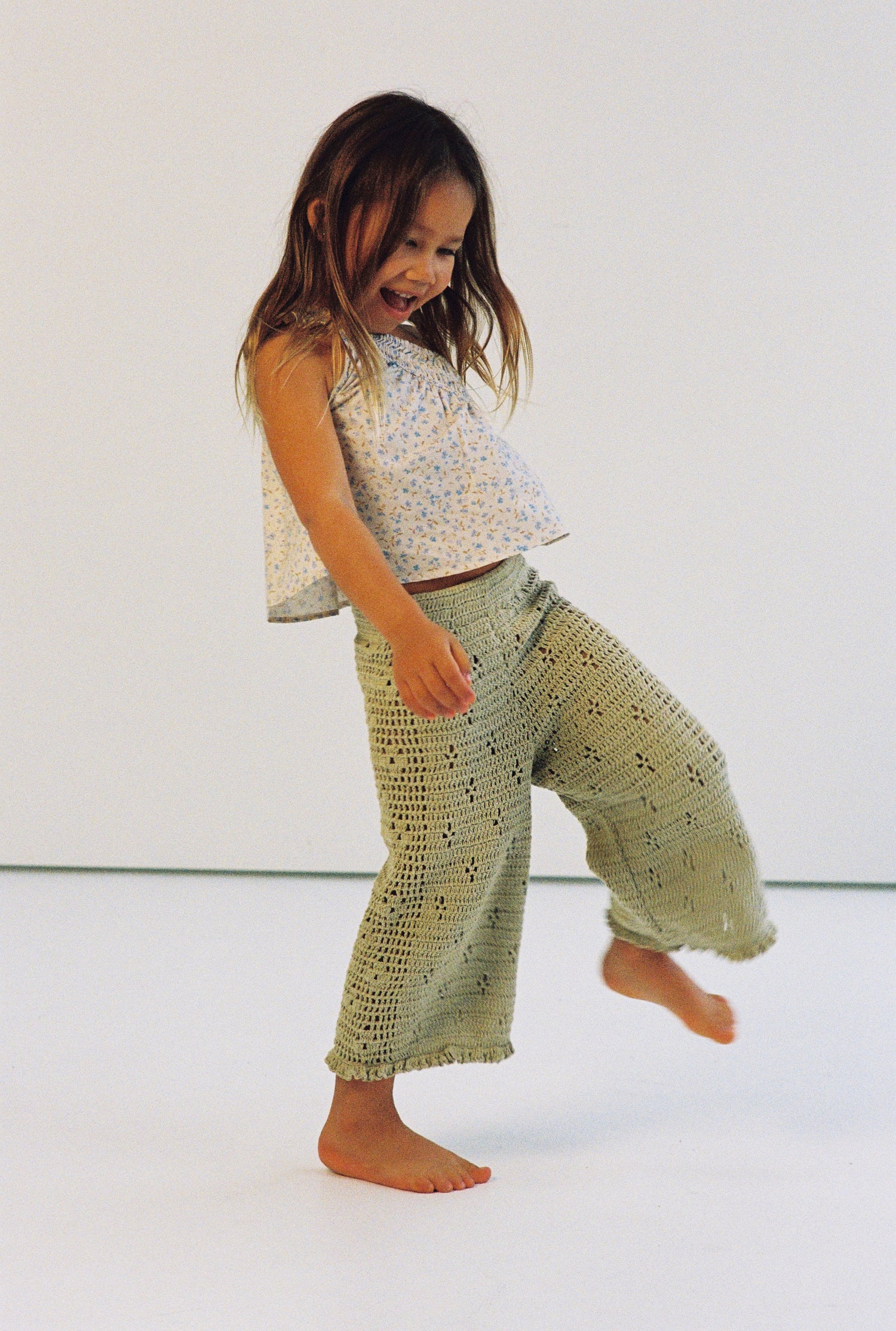 girl wearing one shoulder floral print top with gathers in 100% cotton poplin and 100% cotton handmade crochet pants
