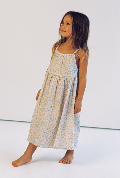 girl wearing 3/4 length floral printed dress made from 100% cotton poplin with thin straps and gathers at the chest and waist