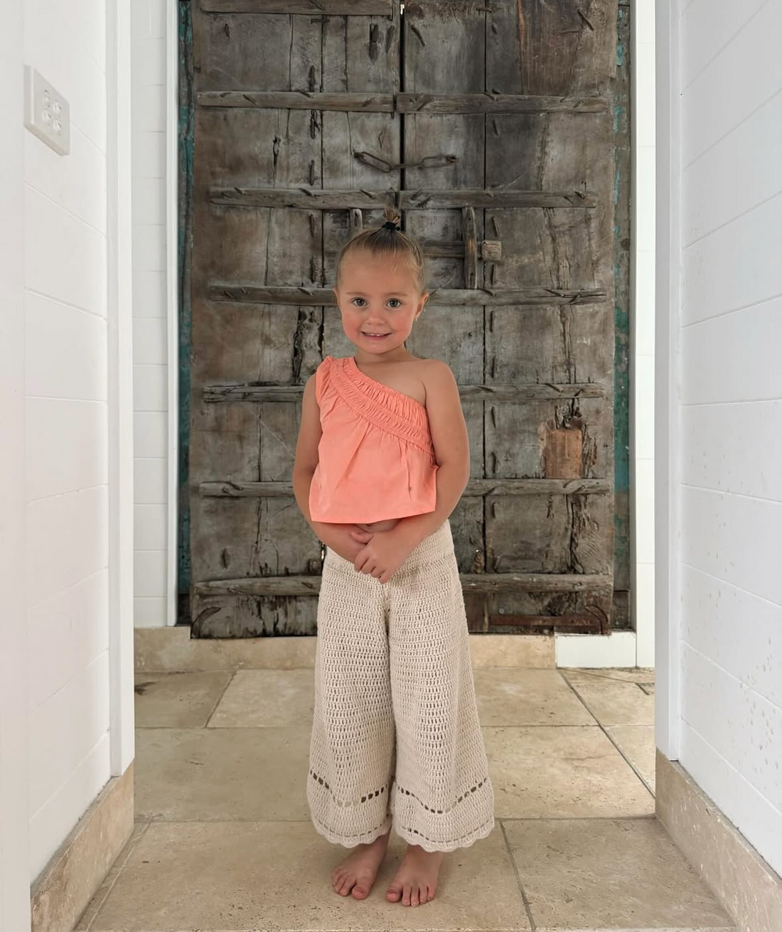 girl wearing woven cotton one shoulder blouse in pink by illoura the label