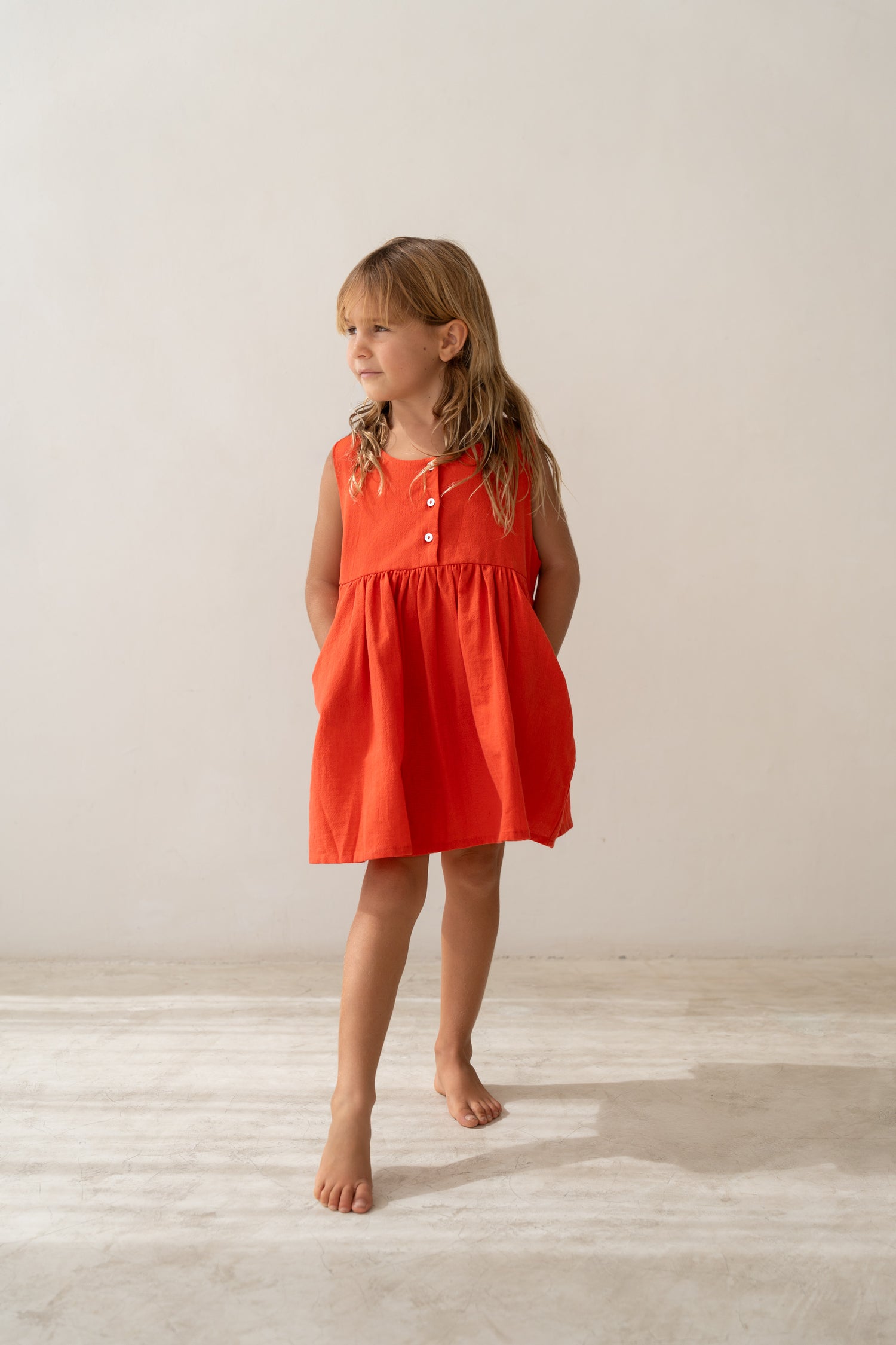 girl wearing cotton pinafore dress in red by Illoura the label