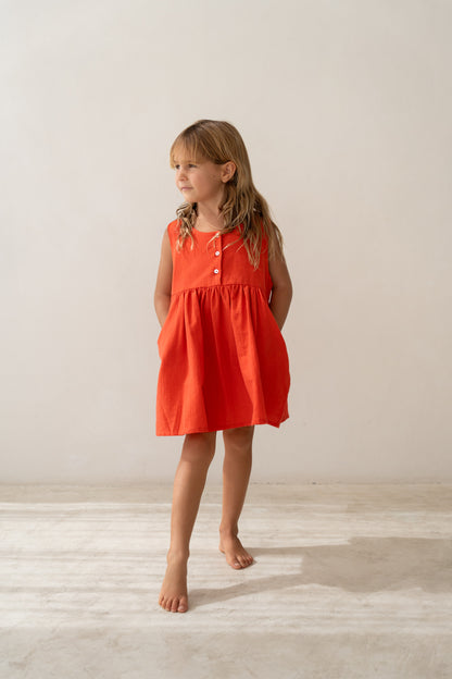 girl wearing cotton pinafore dress in red by Illoura the label