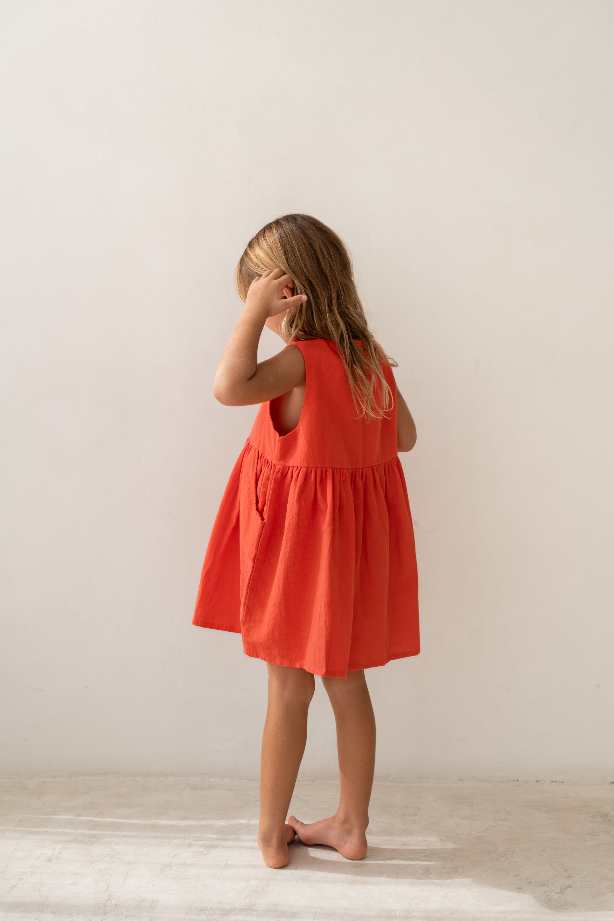 girl wearing cotton pinafore dress in red by Illoura the label