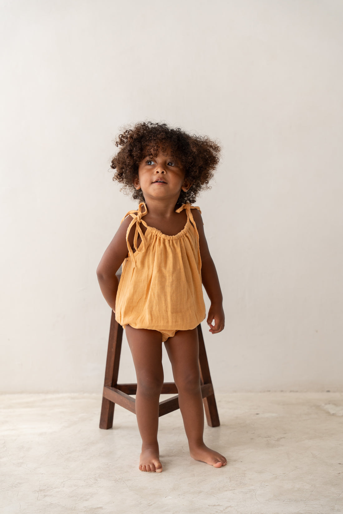 toddler girl wearing orange cotton romper by illoura the label