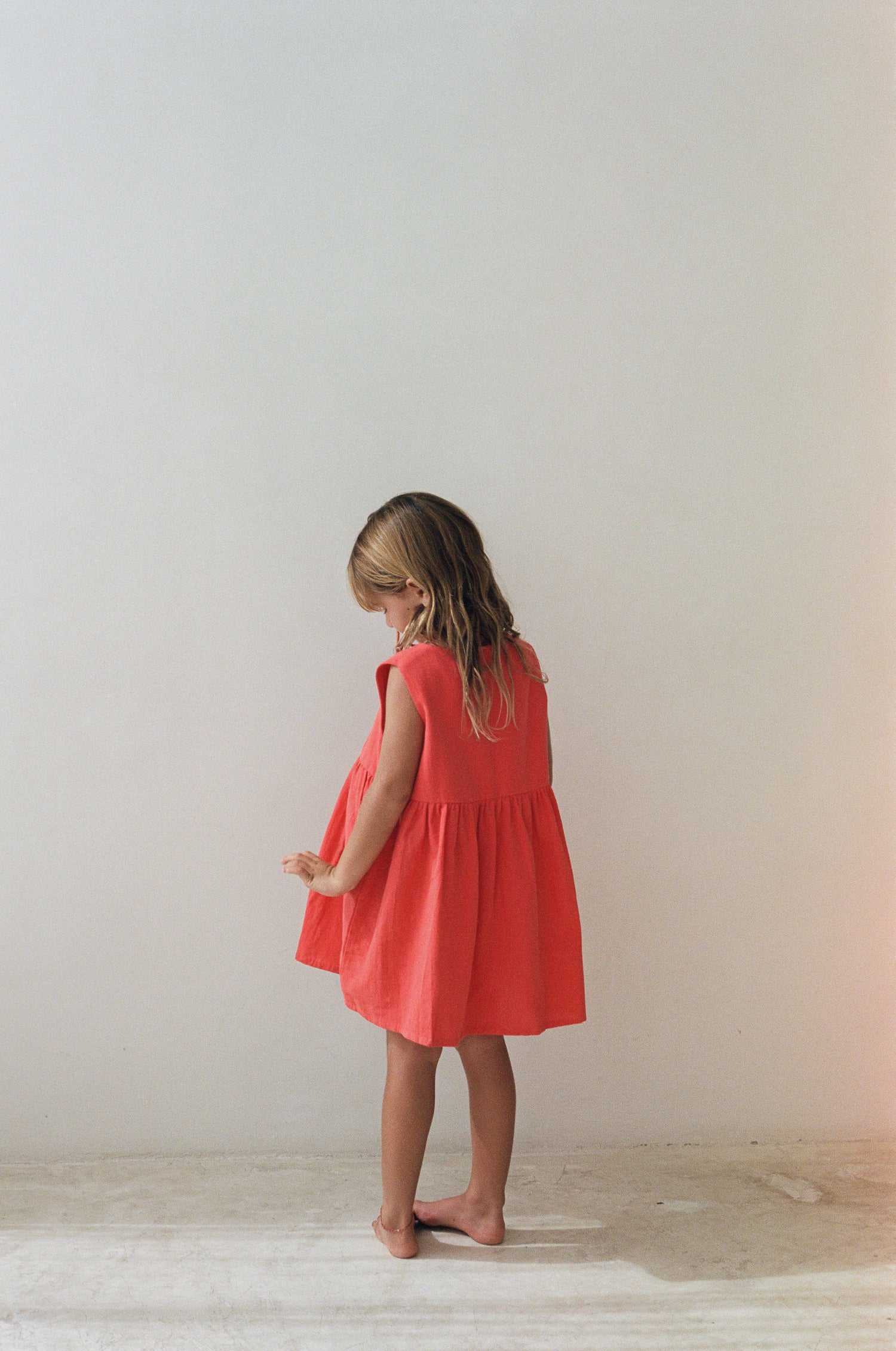 girl wearing cotton pinafore dress in red by Illoura the label
