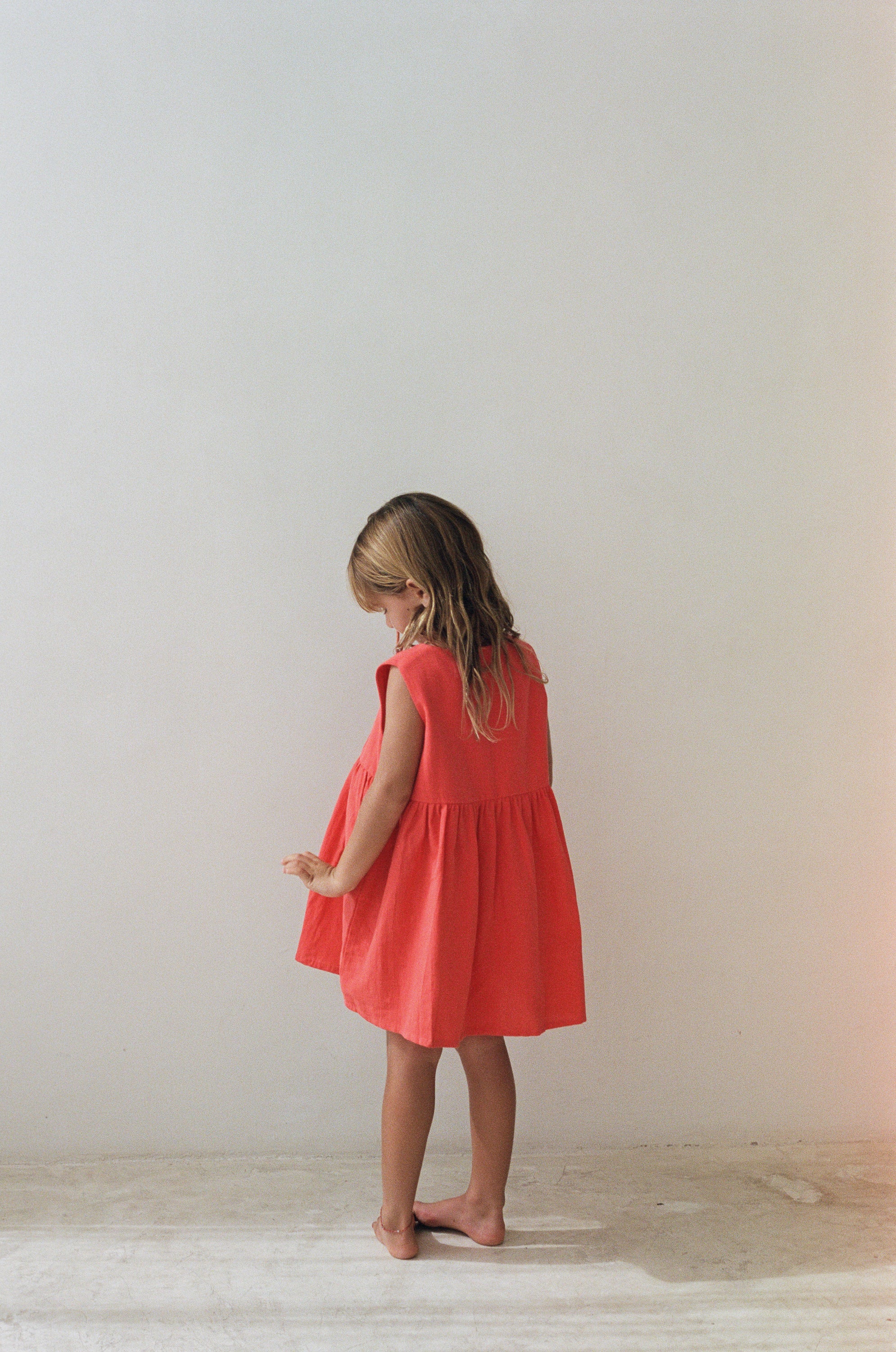 girl wearing cotton pinafore dress in red by Illoura the label