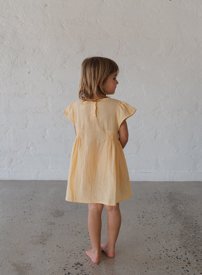 toddler girl wearing 100% cotton dress with shirring and flutter sleeves in butter yellow