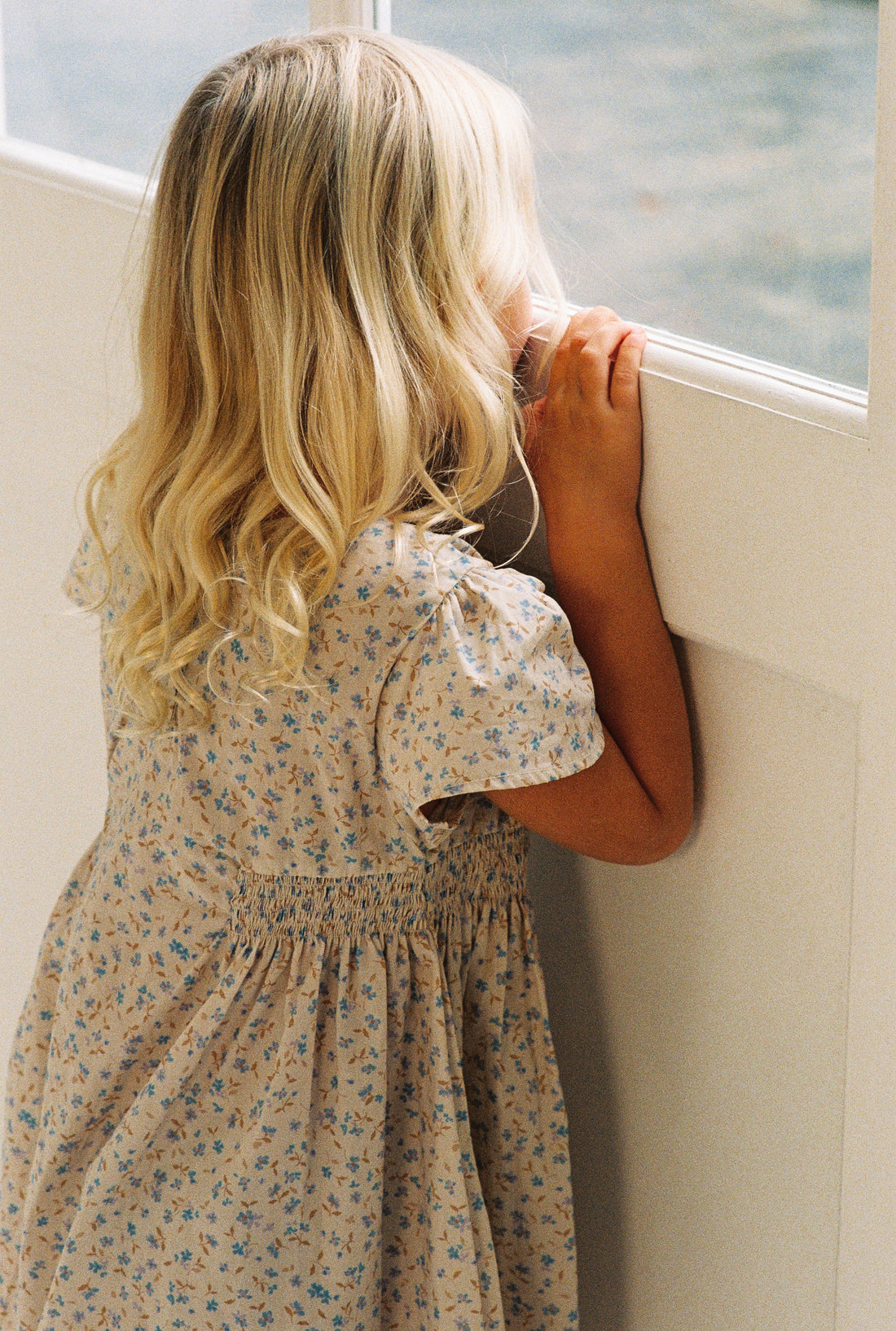 girl wearing floral print mini dress in 100% cotton poplin with shirring and flutter sleeves